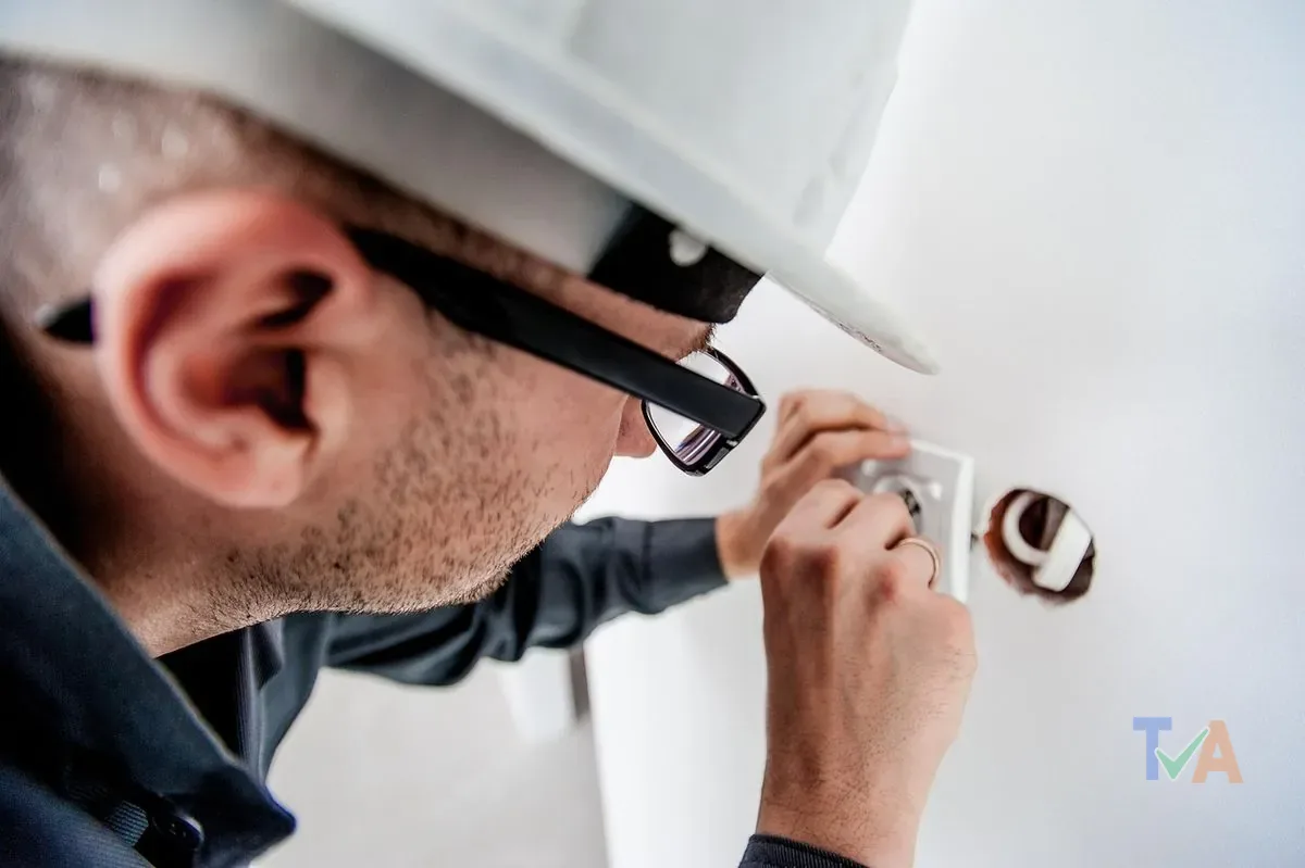 Electrician working on electrical switchboard panel with safety gear