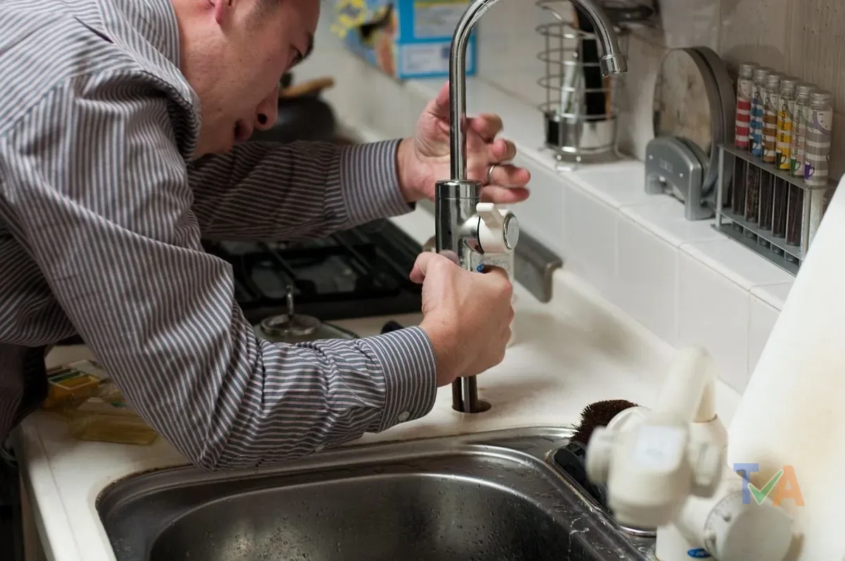 Licensed plumber repairing pipes under kitchen sink in Australian home