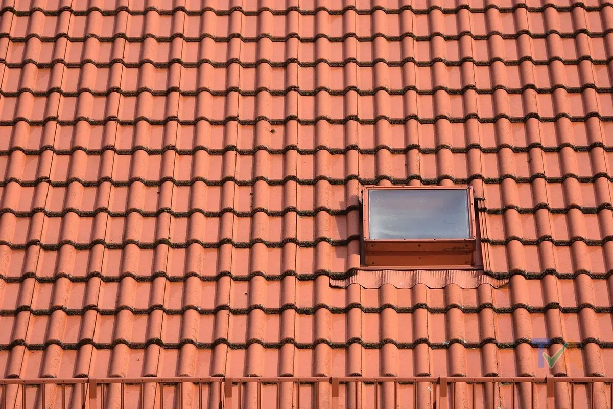 Roofer repairing roof tiles on house with safety harness